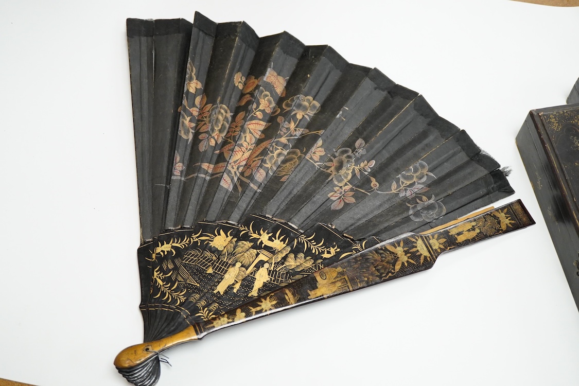 Four 19th century Chinese gilt-decorated black lacquer fans with figure painted leaves, two cased, largest 41cm